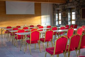 a conference room with tables and red chairs at Lake Cildir Lodge in Çıldır