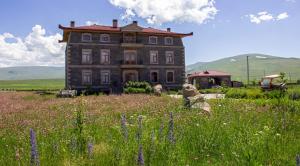 an old house in the middle of a field of flowers at Lake Cildir Lodge in Çıldır