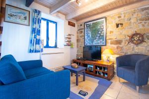 a living room with a blue couch and a tv at Le Gaoulac'H I Vue mer & Grand jardin in Crozon