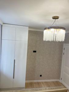 ein Zimmer mit einem weißen Schrank und einem Kronleuchter in der Unterkunft Двухкомнатная квартира in Taldykolʼ