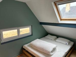 a small bedroom with a bed and two windows at Maison les pieds dans le sable in Blonville-sur-Mer