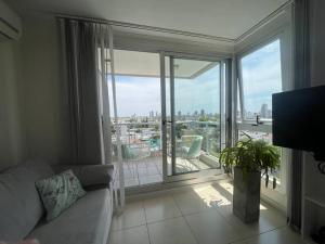 a living room with a couch and a large window at Depto de lujo con cochera y piscina sobre Bv Gálvez in Vuelta del Paraguayo
