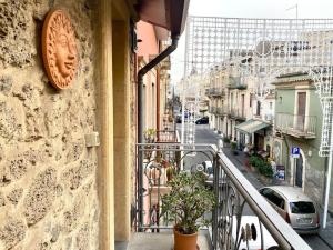 un balcón de un edificio con un reloj en la pared en Casa Angela, en Militello in Val di Catania