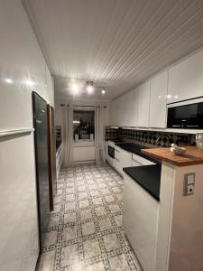 eine Küche mit weißen Schränken und einem Fliesenboden in der Unterkunft Gävle Guest House in Gävle