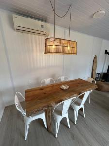 une table en bois avec des chaises blanches et un lustre dans l'établissement Nina casa de playa, à Balneario Buenos Aires