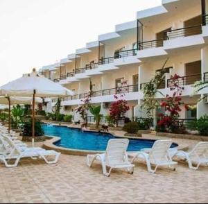 a hotel with a swimming pool with chairs and an umbrella at FOX SAHEL AQUA RESORT ELGOUNa& Kite in Hurghada