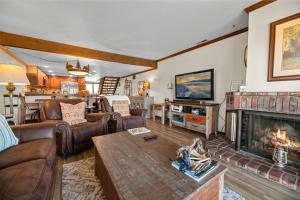 a living room with a fireplace and leather furniture at Shores Lakefront Condo - Walk to Village, Lake Views, Deck with BBQ in Big Bear Lake