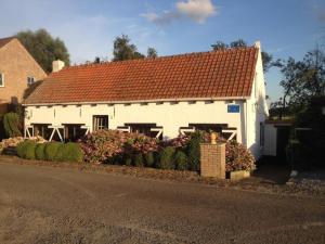 a white house with a red roof on a street at Dike House near Breskens with Stream Garden in Hoofdplaat