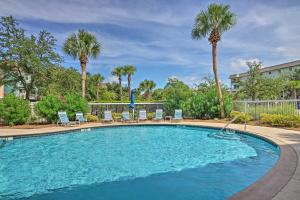 a swimming pool with chairs and palm trees at half Mi to Beach Condo in Hilton Head Resort! in Hilton Head Island