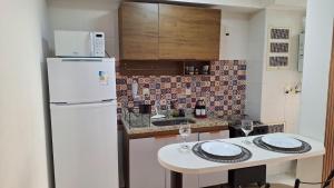 Una cocina con un refrigerador blanco y una mesa blanca. en Apto moderno com varanda, piscina e academia, en Río de Janeiro