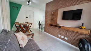 Una sala de estar con un sofá y un televisor en una pared. en Apto moderno com varanda, piscina e academia, en Río de Janeiro