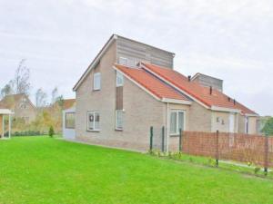 una casa con techo rojo en un patio verde en Coastal Bungalow w Garden, en Breskens