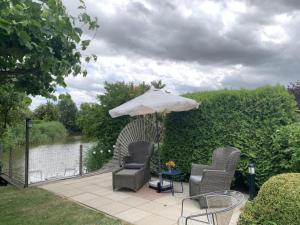 un patio con sillas y una sombrilla junto a un río en Spacious Bungalow near Water, en Breskens