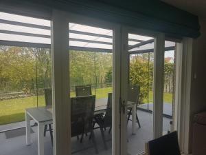 un salón acristalado con puertas correderas de cristal con mesa y sillas en Coastal Bungalow w Garden, en Breskens