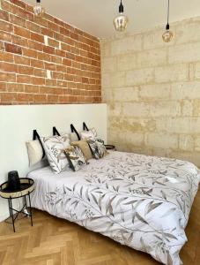 a bed in a room with a brick wall at Charmante Maison La Libournaise +parking in Libourne +27 photos