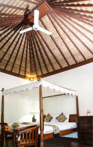 a bedroom with a canopy bed with a ceiling fan at Sunhouse Guesthouse in Sanur