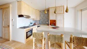 a kitchen with wooden cabinets and a kitchen island with chairs at Strandwohnung Taghazout mit Meerblick, Terrasse, Garten & Pool 2 Min zum Surfspot in Taghazout +13 photos