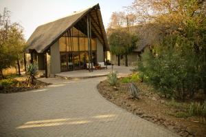 a building with a gambrel roof and a walkway at Morokolo Safari Lodge Self-catering in Pilanesberg