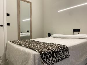 a bedroom with a bed with a black and white blanket at Apartamento Plaza del Cabildo II - Sanlúcar Centro in Sanlúcar de Barrameda