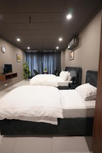 a hotel room with three beds and a television at Hotel Crossroads in Islamabad