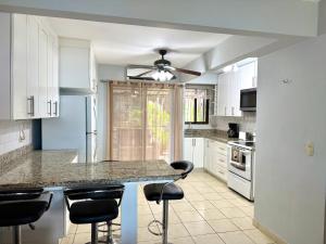a kitchen with white cabinets and a counter with bar stools at Coco Maya 2b2b Villa in Coco