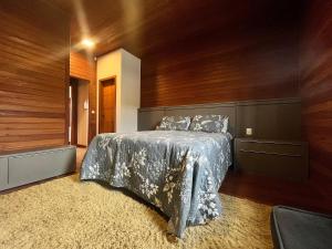 邦比尼亚斯B167 - Casa de Alto Padrão com Piscina Privativa e Espaço Gourmet a 450m do Mar na Praia de Mariscal - Bombinhas-SC的卧室里有一张床，墙是木的 更多33张照片