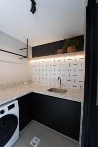 eine Küche mit Spüle und Waschmaschine in der Unterkunft Lofts amplos e sofisticados a 600m da Vila Germânica in Blumenau