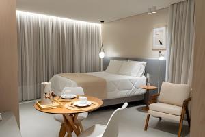 ein Hotelzimmer mit Bett, Tisch und Stühlen in der Unterkunft Lofts amplos e sofisticados a 600m da Vila Germânica in Blumenau + 20 Fotos