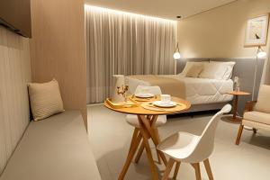 ein Hotelzimmer mit Bett, Tisch und Stühlen in der Unterkunft Lofts amplos e sofisticados a 600m da Vila Germânica in Blumenau