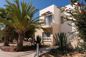 ein Gebäude mit Palmen davor in der Unterkunft Mountain & Seaview Penthouse in a Holiday Village2 in Ayios Yeoryios