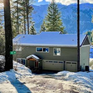 a house with a snow covered roof in the snow at Alpine Lodge - Epic Mountain Views, Hot Tub, 2 Miles to Town in Leavenworth