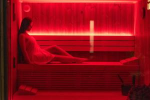 a woman sitting on a bench in a red light at Boulevard Boutique Suites in Łeba
