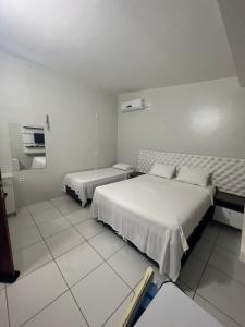 two beds in a room with white tiled floors at Suíte Brisa Mar Villa brisa icaraizinho in Amontada