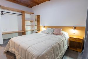 a bedroom with a large white bed and shelves at Los Fresnos in El Calafate