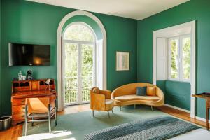 a living room with green walls and a chair and a desk at Solar dos Cantos Botanic House & Garden in Ponta Delgada