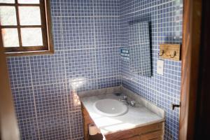 a blue tiled bathroom with a sink and a mirror at Pousada do Artista in Conceição da Ibitipoca +72 photos