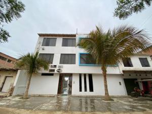 a white building with two palm trees in front of it at Rio Hotels Mancora in Máncora