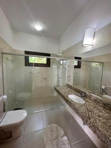 Casa Dendê - Arraial D'Ajuda في ارايال دايودا: حمام مع حوض ومرحاض ومرآة