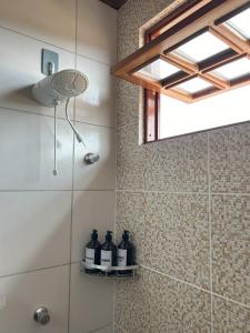 a bathroom with a shower with bottles on a shelf at Bella Casa Ipê - APA Barra de Mamanguape in Rio Tinto