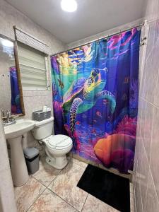 a bathroom with a sea turtle shower curtain at NicoleMary Apartments Parguera in Lajas +14 photos