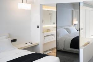 a white bedroom with a bed and a mirror at Swiio Hotel Daan in Taipei