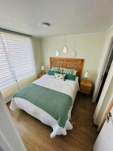 a bedroom with a large bed with a green blanket at Departamentos Real in Santiago +26 photos
