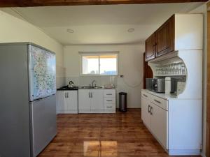 una cucina con mobili bianchi e un frigorifero di Cabaña en Malalcahuello a Malalcahuello Altre 5 foto