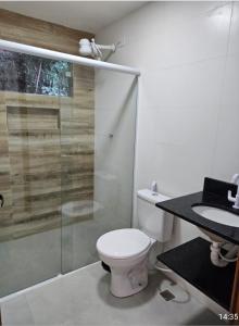 a bathroom with a toilet and a glass shower at Chalés Pé na Areia - Ubatuba in Ubatuba