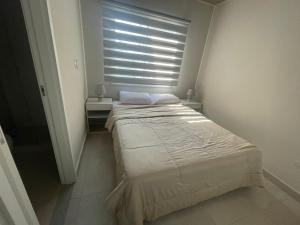 a bedroom with a bed and a window with blinds at Dpto Edificio Marlin Luque in Luque