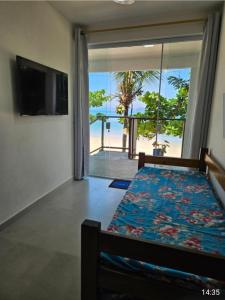 a bedroom with a bed with a view of the beach at Chalés Pé na Areia - Ubatuba in Ubatuba