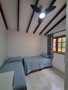two beds in a room with a ceiling fan at Sítio Quinta da mata - Casa Amarela in Pirenópolis