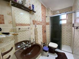 une salle de bain avec un lavabo et des toilettes dans l'établissement Apartamento Lelis - Descanso para a família e seu pet, pertinho do mar - praia Guarujá - SP, à Guarujá