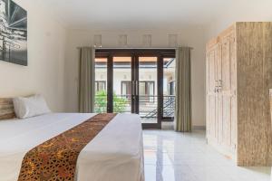 a bedroom with a bed and a sliding glass door at Azalea Homestay & Villa in Canggu