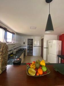 un bol de fruits et légumes sur une table dans une cuisine dans l'établissement Casa confortável e espaçosa em Búzios, à Armacao dos Buzios